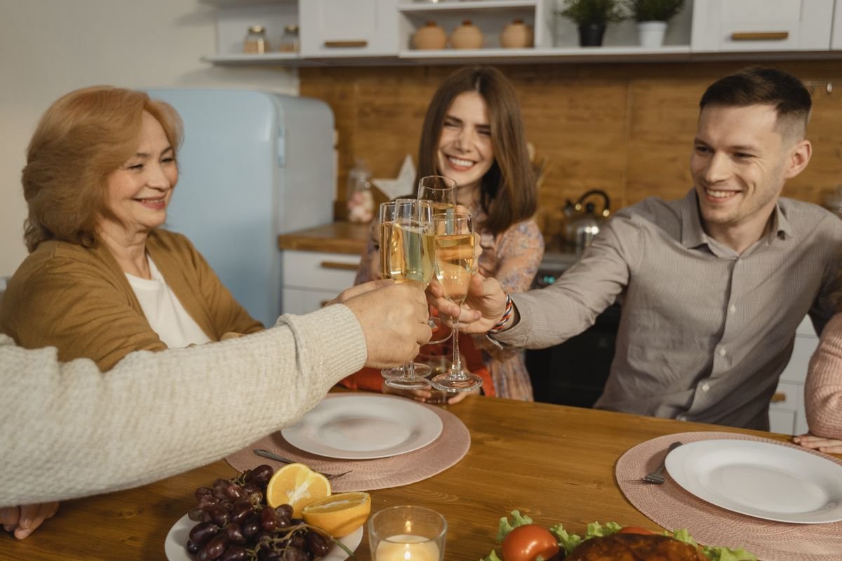 Família brindando com taças de espumante à mesa em uma confraternização em casa